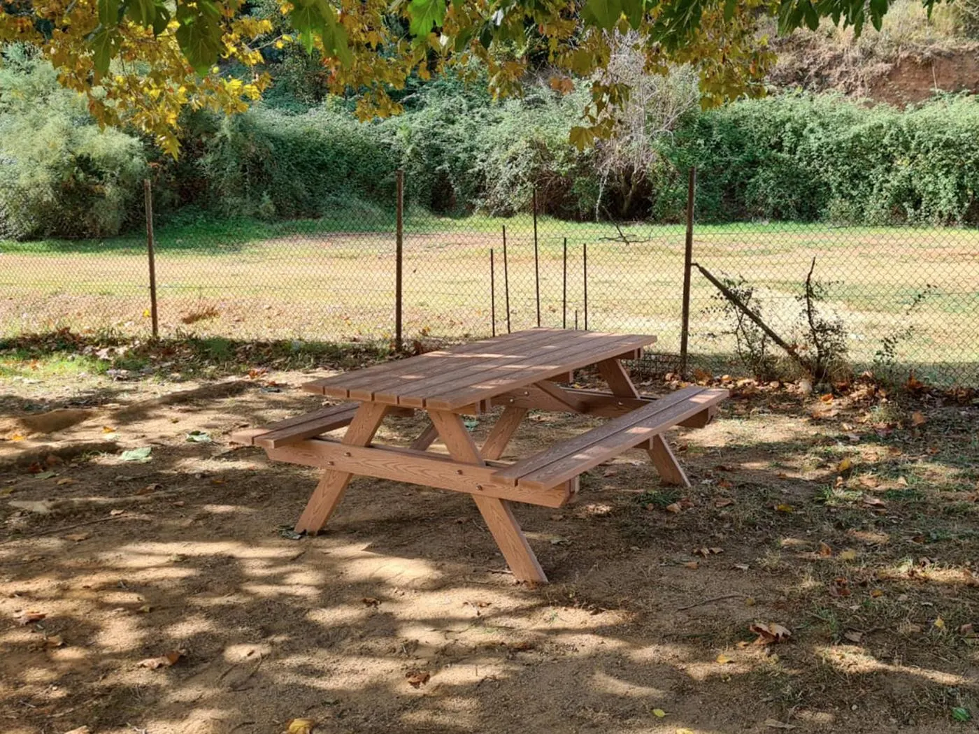Mesa de picnic de madera en un área recreativa con árboles