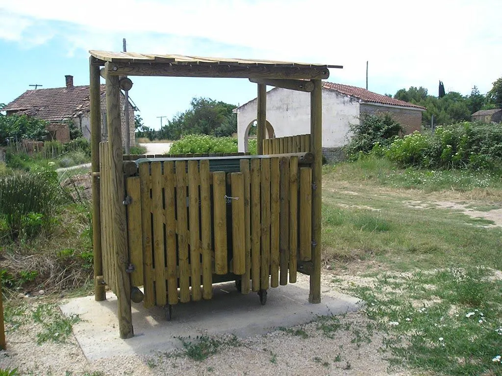 Cubrecontenedor de madera a medida con tejado a un agua, junto a una casa