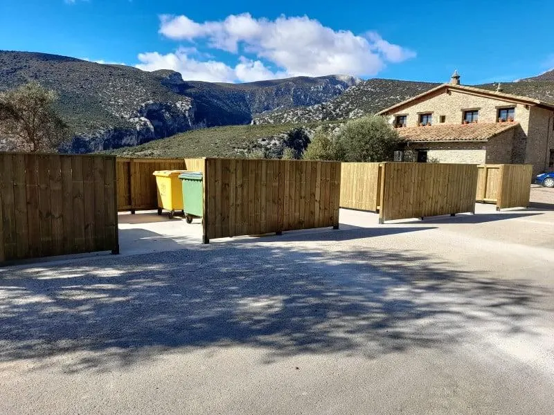 Cubrecontenedor de madera por módulos rectos que oculta varios contenedores en un pueblo de montaña