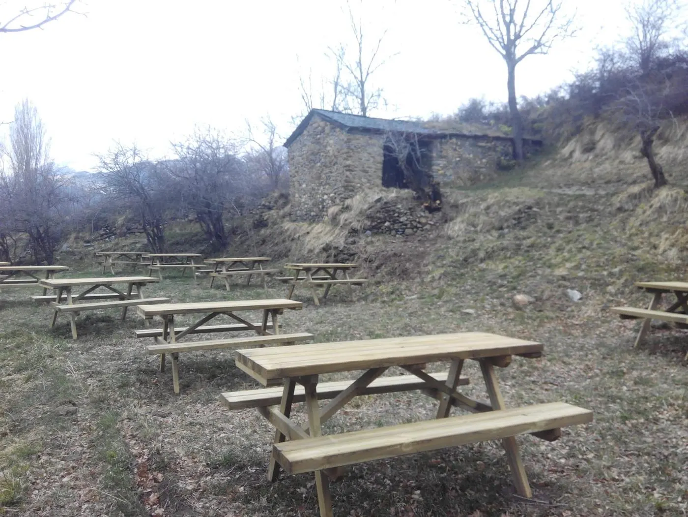 Área recreativa con varias mesas de picnic de madera instaladas en una ladera