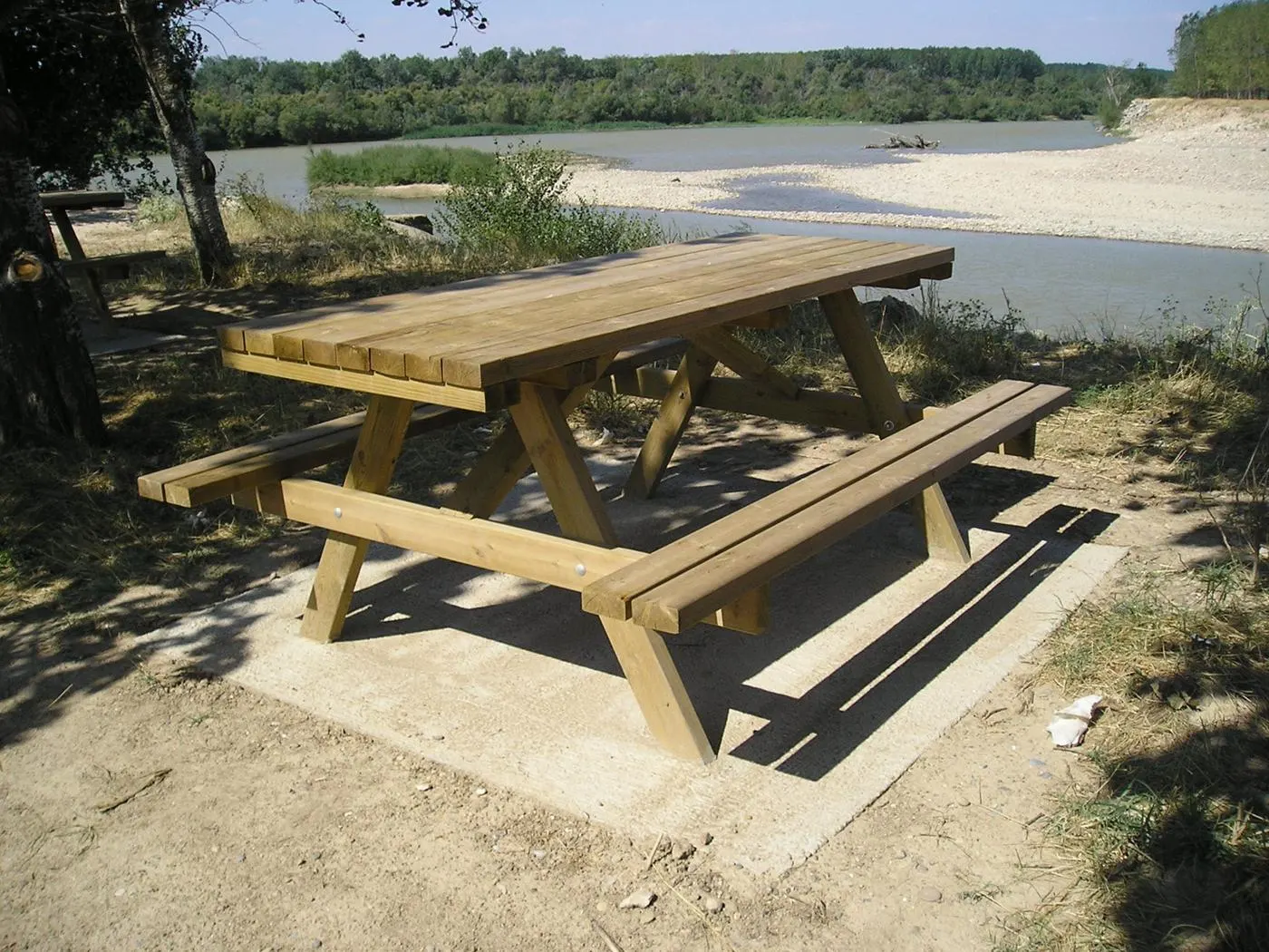 Mesa de picnic de madera con bancos integrados en un área recreativa