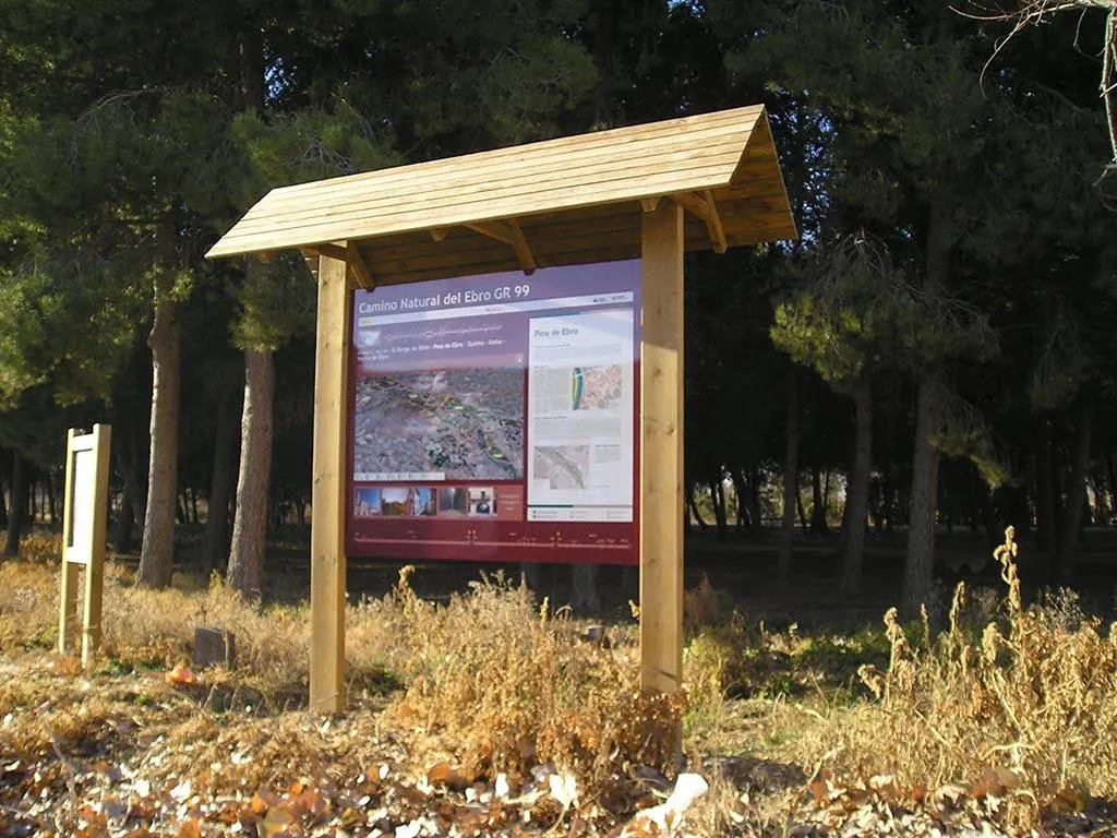 Cartel de madera modelo CN-00 con tejado a dos aguas y panel informativo de un camino natural en un pinar