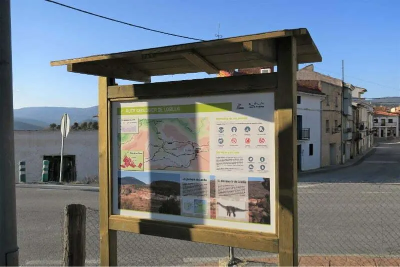 Cartel de madera estándar vertical con tejado a dos aguas en una calle de pueblo