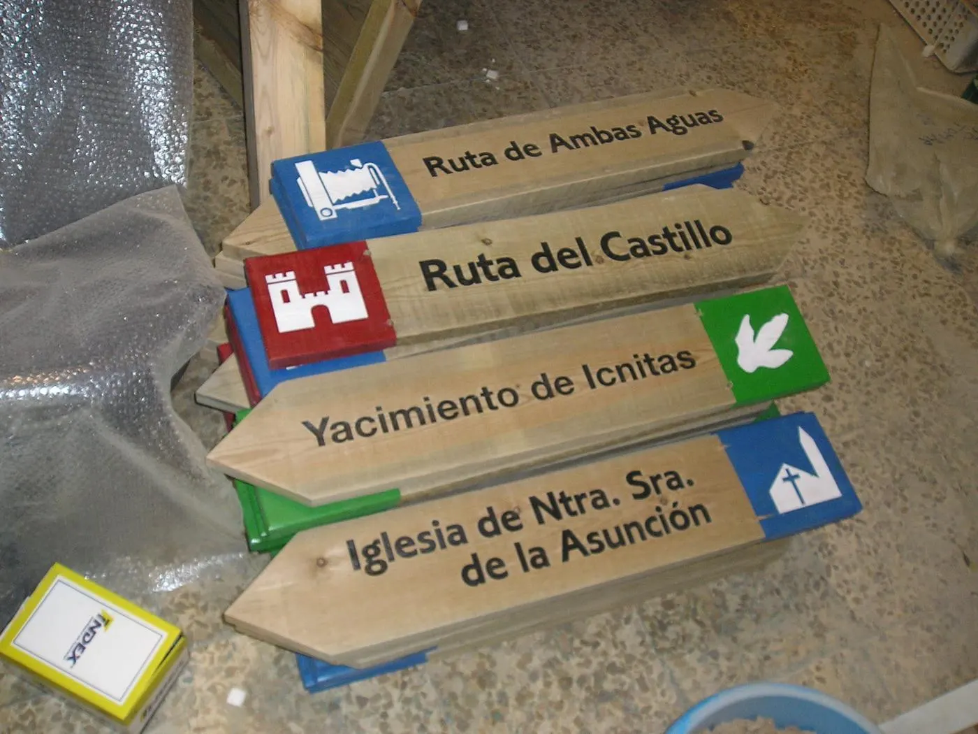 Flechas de madera grabadas y pintadas con pictogramas, preparadas en el taller antes de su instalación