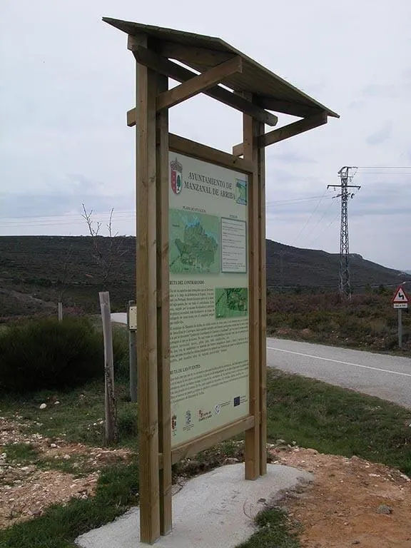 Cartel de madera modelo Manzanal con tejadillo y panel informativo en un camino rural