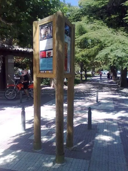 Cartel rústico triple de madera con tres caras informativas en una calle